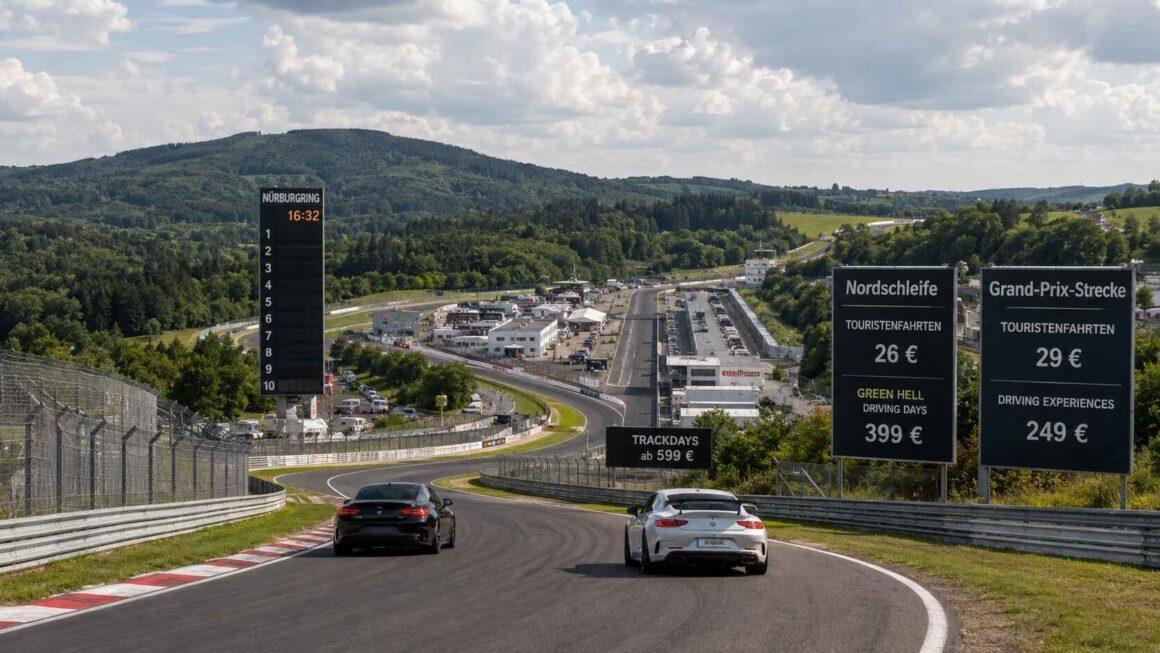 Deux Porsche sur circuit asphalté, encadrées par de grands panneaux noirs affichant les tarifs de la Nordschleife et du GP.